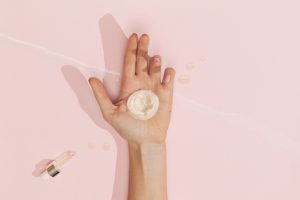 Hand einer Frau, auf der sich eine Creme befindet